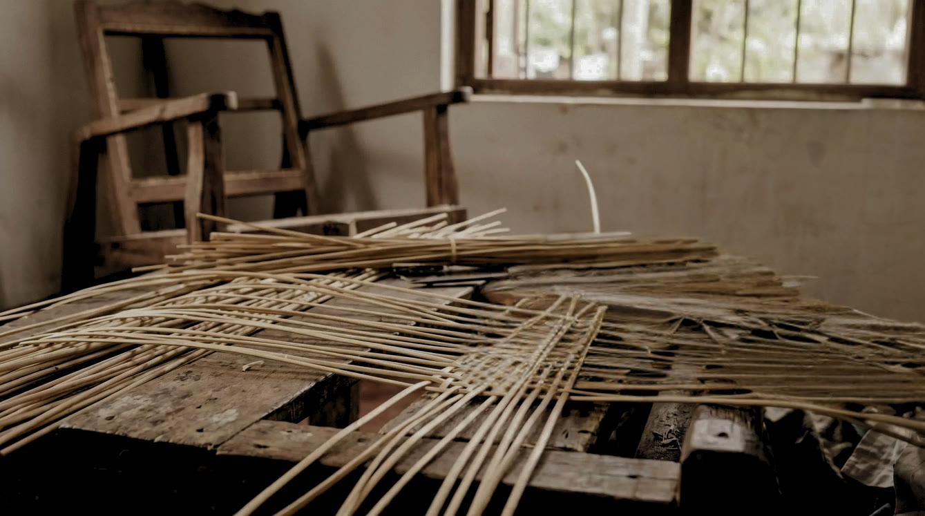 Cane strips being woven by hand on a wooden workbench